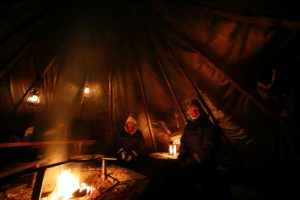 couple sit by fire in tent