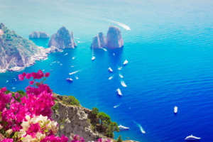 Boats floating around an island in a deep blue sea in Italy