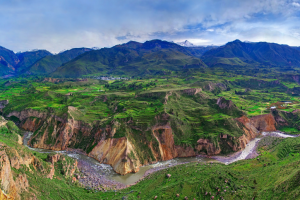 Water running through Colca canyon with mountains in the background