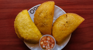 A plate of traditional colombian empanadas with a side of chilie sauce